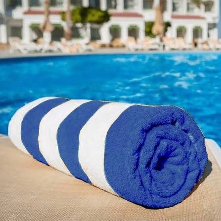 Rolled blue and white striped pool towel by a swimming pool