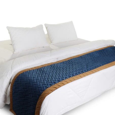 Navy blue bed runner with tan trim on a white bed